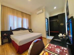 a bedroom with a bed and a television and a desk at Quds Royal Hotel in Surabaya