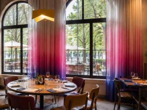 a dining room with tables and chairs and windows at DAFFY Hôtel in Briançon