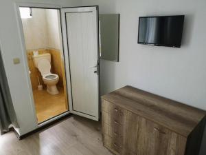 a bathroom with a toilet and a television in it at Къща за гости ПЕРФЕКТО in Chernomorets