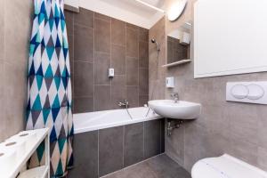 a bathroom with a sink and a tub and a toilet at Nova City Apartments in Budapest +61 photos