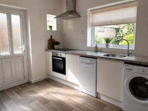 a white kitchen with a sink and a dishwasher at Amy's place in Warrington