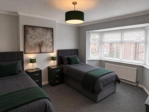 a bedroom with two beds and two windows at Amy's place in Warrington