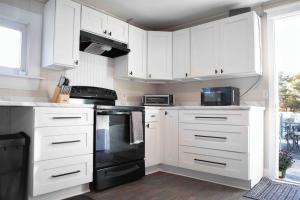 a kitchen with white cabinets and black appliances at Cozy 3BR Coastal Retreat Private Yard & Fire Pit 5 Min to Beach! in Old Orchard Beach