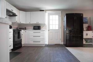 a kitchen with white cabinets and a black refrigerator at Cozy 3BR Coastal Retreat Private Yard & Fire Pit 5 Min to Beach! in Old Orchard Beach +32 photos