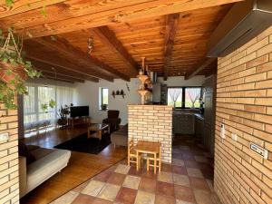 a living room with wooden ceilings and a brick wall at Apkó Vendégház in Őriszentpéter