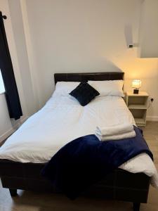a bed with white sheets and a black head board at Accessible Town Centre 1 bed Flat Kettering Wi-FI in Kettering