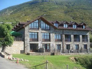 un grand bâtiment en pierre avec une montagne en arrière-plan dans l'établissement Hotel Palazio, à Nerín