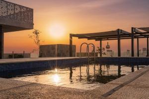 a swimming pool on the roof of a building with the sunset at Stella Stays Olaya Tower 1 - Furnished Apartments in Riyadh