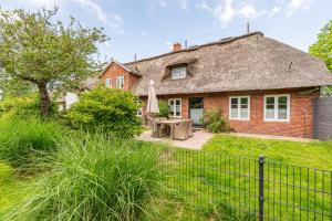 ein Backsteinhaus mit Reetdach in der Unterkunft FeWo Watt-Lounge zwischen Husum und Nordstrand in Wobbenbüll
