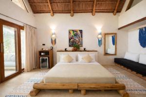 a bedroom with a large bed and a couch at MONEA The Nest in Paje