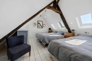 a attic bedroom with two beds and a chair at La maisonette Ti Arzou in Le Conquet
