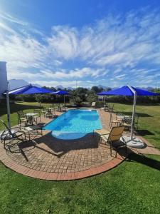 a pool with chairs and tables and blue umbrellas at Town Lodge George in George