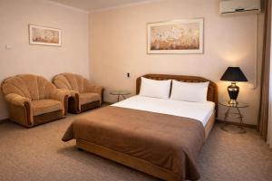 a hotel room with a bed and two chairs at Apartment Deluxe on Moscow Avenue in Chişinău