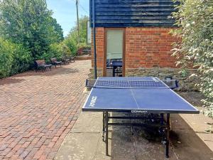 a ping pong table sitting in front of a brick building at Thornsdale Oast House in Stone