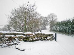 a snow covered path with a stone wall and trees at Thornsdale Oast House in Stone