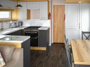 a kitchen with white cabinets and a black stove at Apple Grove 110 - Ukc9393 in Exmouth