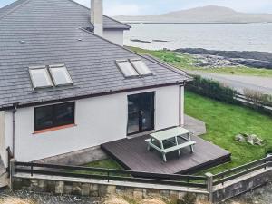 a white house with a picnic table on a deck at Sealladh Lingeigh in Pollachar