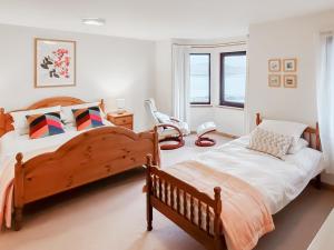 a bedroom with two beds and a chair in it at Sealladh Lingeigh in Pollachar