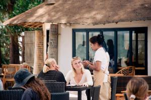 a woman standing next to a woman sitting at a table at Long Beach Chalets - SHA Extra Plus in Ko Lanta +48 photos