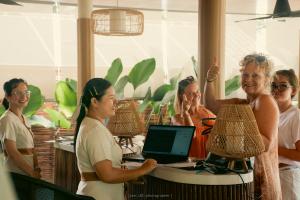 a group of women standing around a table with a laptop at Long Beach Chalets - SHA Extra Plus in Ko Lanta