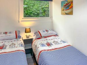 two twin beds in a room with a window at Sandy Cott in Kilkhampton