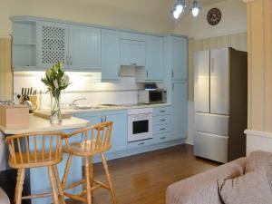 a kitchen with blue cabinets and a table and chairs at Kinnelhook Holiday Cottage in Templand