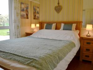 a bedroom with a large bed with two night stands and two lamps at Kinnelhook Holiday Cottage in Templand