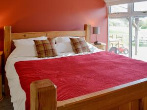 a bedroom with a large bed with a red wall at Kinnelhook Holiday Cottage in Templand +9 photos