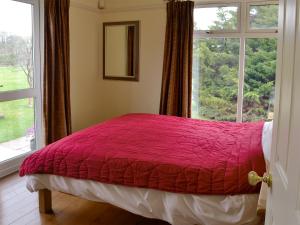 a bed in a room with a large window at Kinnelhook Holiday Cottage in Templand