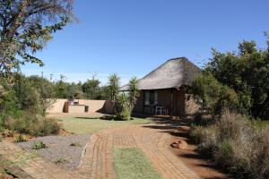 a small hut with a thatched roof in a field at Tava Lingwe Game Lodge & Wedding Venue in Parys