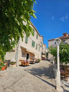 a stone building with tables and benches on a street at Apartmani Banić Apartman 5 in Postira
