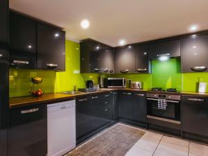 a kitchen with black cabinets and green walls at St Hildas Rest in Hinderwell