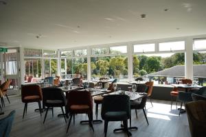 a dining room with tables and chairs and windows at Westhill Country Hotel in Saint Helier Jersey