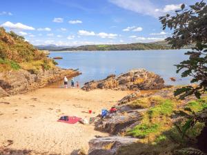 a group of people walking on a beach near a body of water at Fron - Cottage in Mynfford