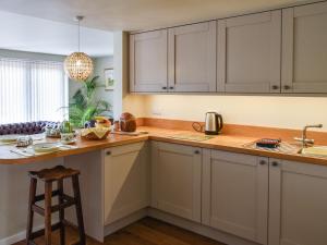 a kitchen with white cabinets and a wooden counter top at Swallowtail Lodge in Brundall