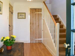 a hallway with a wooden door and stairs at Avenel Cottage in Town Yetholm