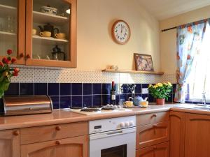 a kitchen with a counter and a clock on the wall at Avenel Cottage in Town Yetholm
