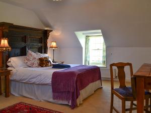 a bedroom with a bed with a teddy bear on it at Avenel Cottage in Town Yetholm