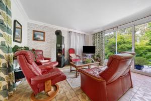 a living room with red leather chairs and a tv at Chambres D'hôtes De Kersehen in Plouider