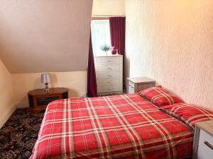 a bedroom with a bed with a red plaid blanket at Ramsgate Corner Retreat in Ramsgate