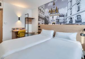a bedroom with a large white bed and a desk at B&B HOTEL Bordeaux Mérignac Cadera Aéroport in Mérignac