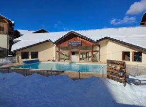 a house with a swimming pool in the snow at Résidence les églantines in Le Mélézet