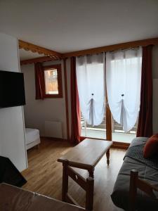 a living room with white curtains and a coffee table at Résidence les églantines in Le Mélézet
