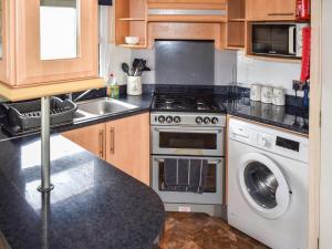 a kitchen with a stove and a washing machine at Apple Grove 24 in Exmouth