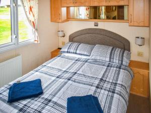 a bed in a small room with two blue pillows at Apple Grove 24 in Exmouth +4 photos