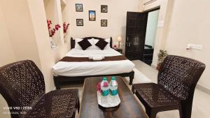 a bedroom with a bed and two chairs with drinks on a table at Parinuj homestay in Chittaurgarh