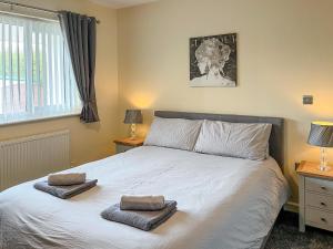 a bedroom with a bed with two towels on it at White Towers - Hw7625 in Llandwrog