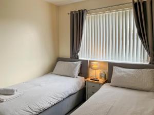 two beds in a small room with a window at White Towers - Hw7625 in Llandwrog