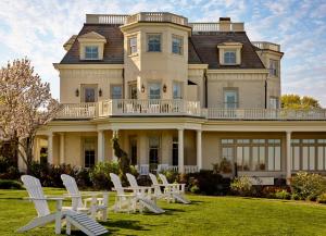 a large house with white chairs in front of it at The Chanler at Cliff Walk in Newport