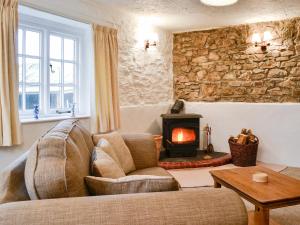 a living room with a couch and a wood stove at Cider Cottage - E5576 in Warkleigh